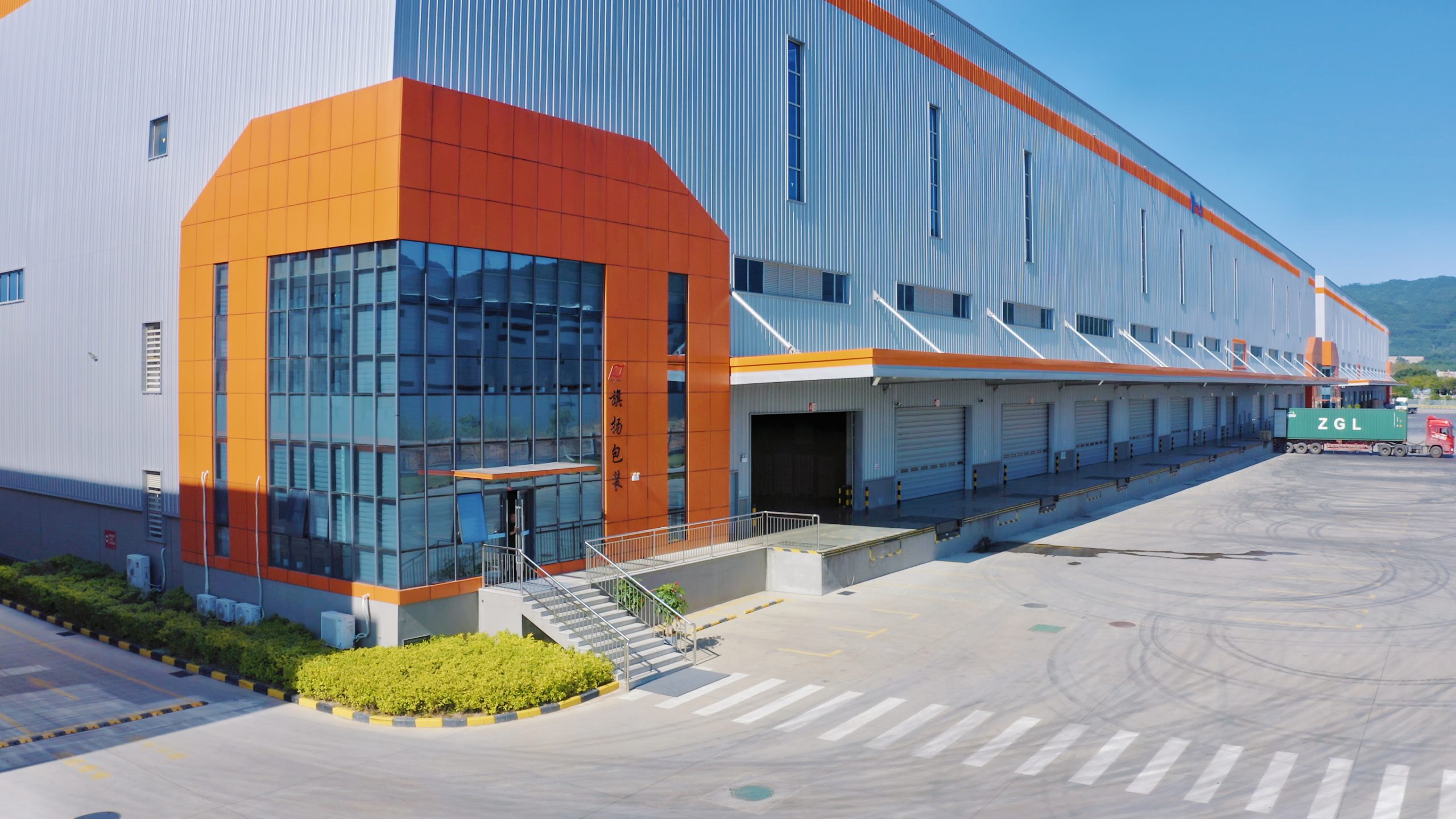 Qiyang Packaging modern factory warehouse exterior, large paper packaging manufacturing plant with loading dock and container truck