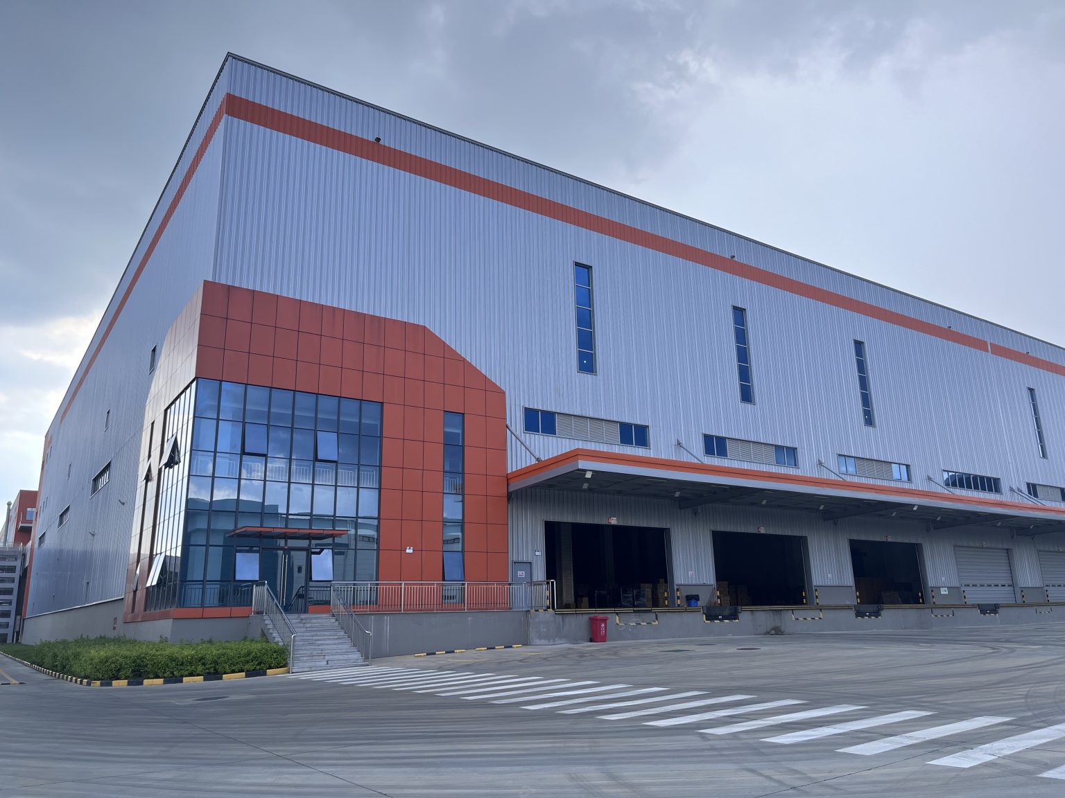 Qiyang Packaging modern steel‑structure factory warehouse exterior, paper packaging manufacturing plant with loading bays